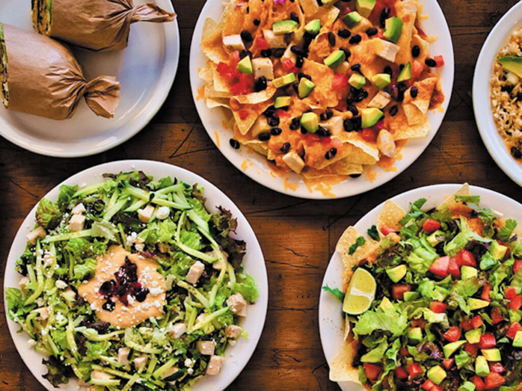 Four plates of assorted foods arranged on a table, showcasing diverse culinary options.