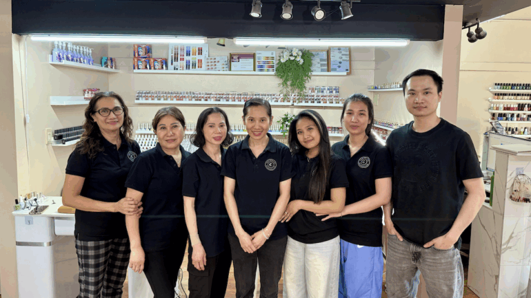 Seven workers at Chloe nails spa smiling in a nail salon.