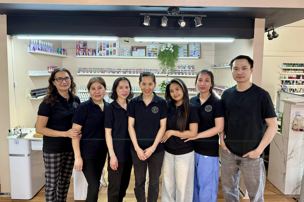 Seven workers at Chloe nails spa smiling in a nail salon.