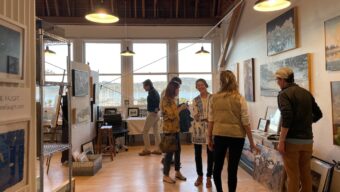 People mill around anc chat in an art gallery.