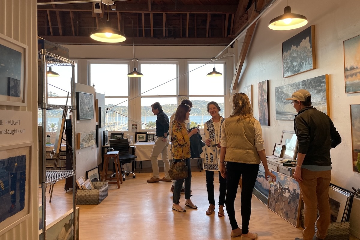 People mill around anc chat in an art gallery.