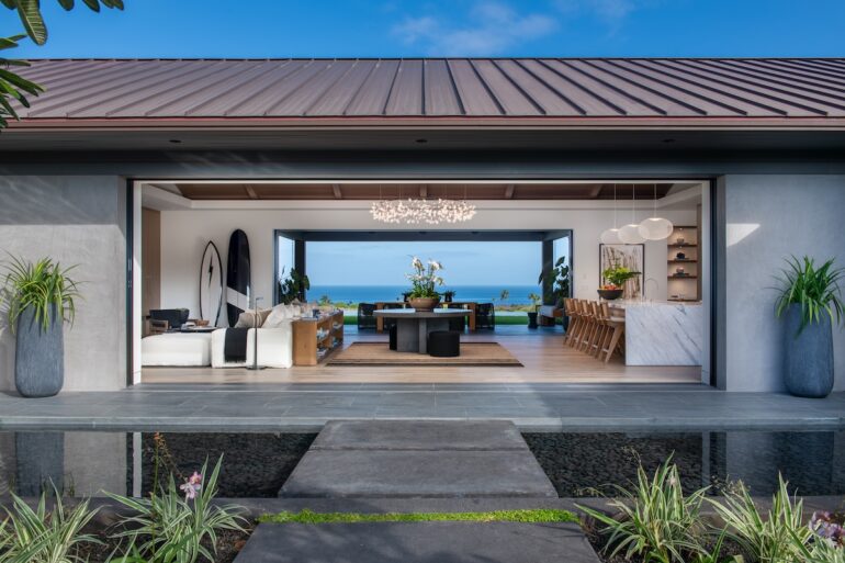 A photo of a house with large windows at the back overlooking the bay.