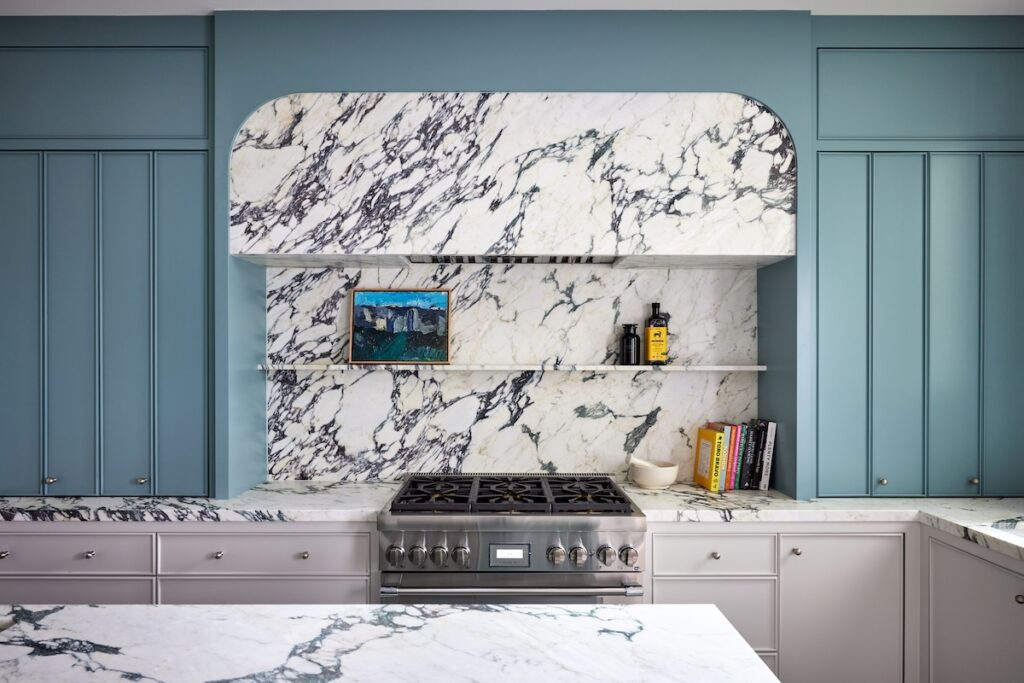 A kitchen with marble countertops and blue shiplap backsplash.
