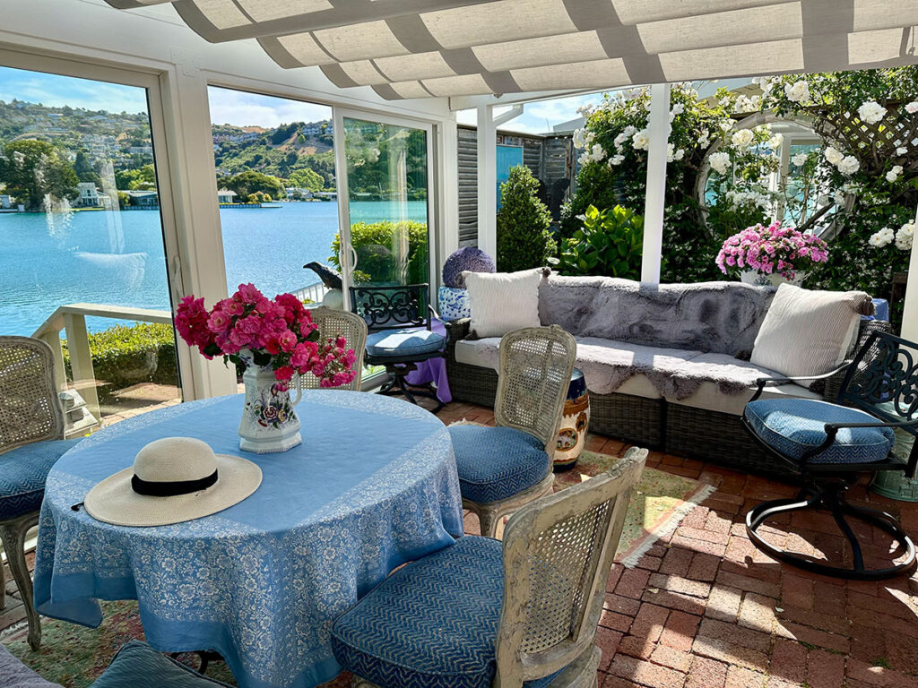 A sunroom patio with a table and chairs, showcasing a beautiful view of the lake and surrounding lagoon.