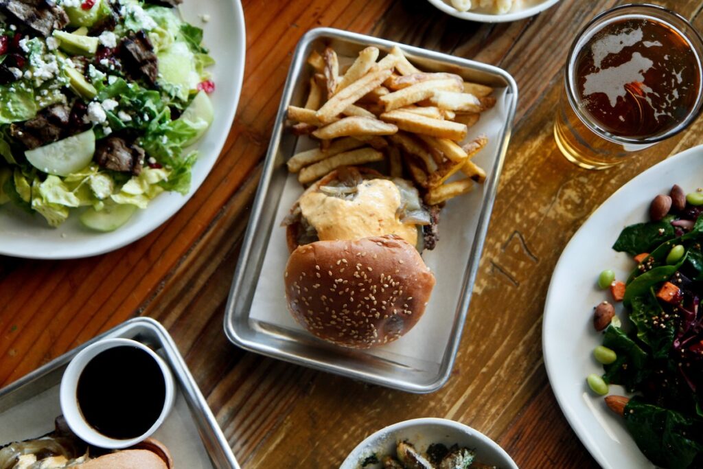 An aerial shot of a table with a burger and fries and some sides and drinks.