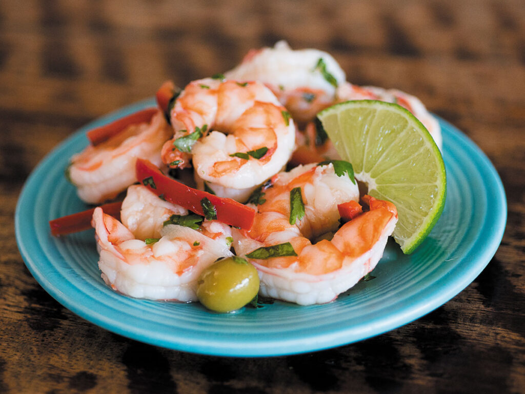 A plate featuring shrimp, colorful peppers, and lime slices arranged appetizingly.