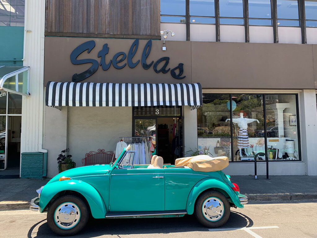 A small car parked in front of a store, with the store's entrance visible in the background.
