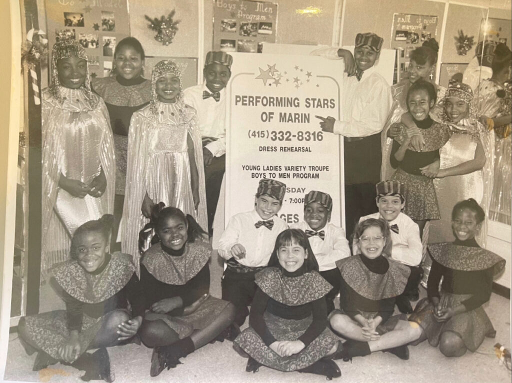 Group of young Performing Stars in Egyptian-inspired costumes pose at a dress rehearsal with a signboard in the center.