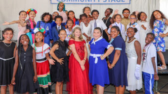 Performing Stars children smiling brightly on the Kaiser Permanente Community Stage in colorful, formal, and cultural attire.