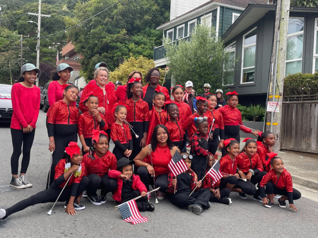 Performing Stars baton troupe dressed in sparkly red outfits pose during a July 4th parade celebration.