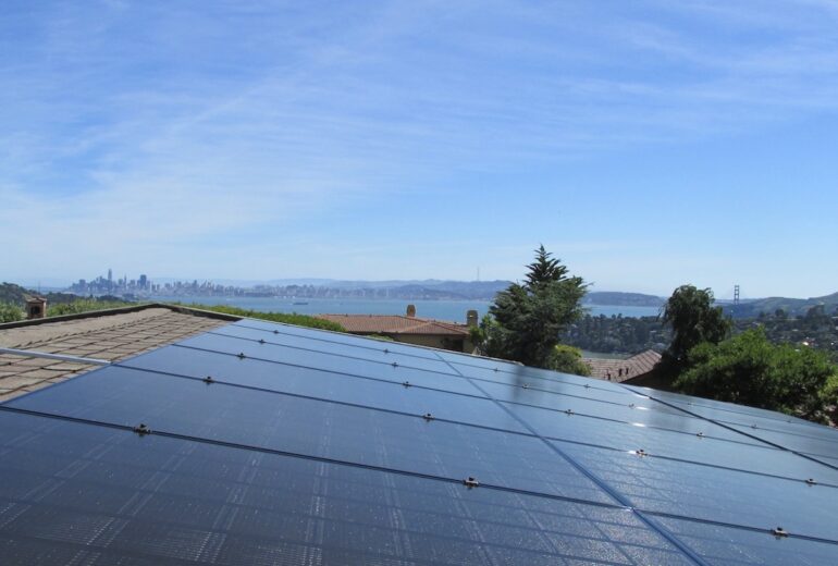 Solar panels on the top of a building with a view of SF.