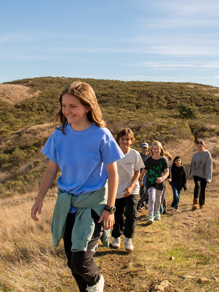 A group of children hiking on a scenic trail enjoying the outdoors and each other's company.
