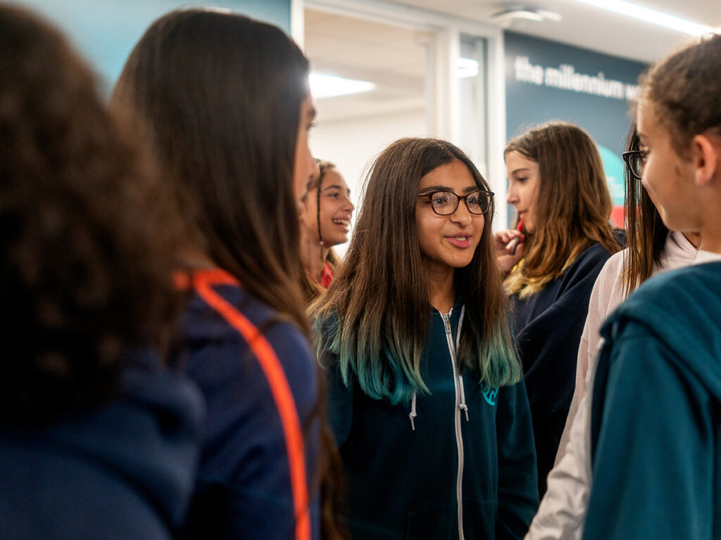 A group of girls engaged in conversation in a cozy room, sharing smiles and laughter.