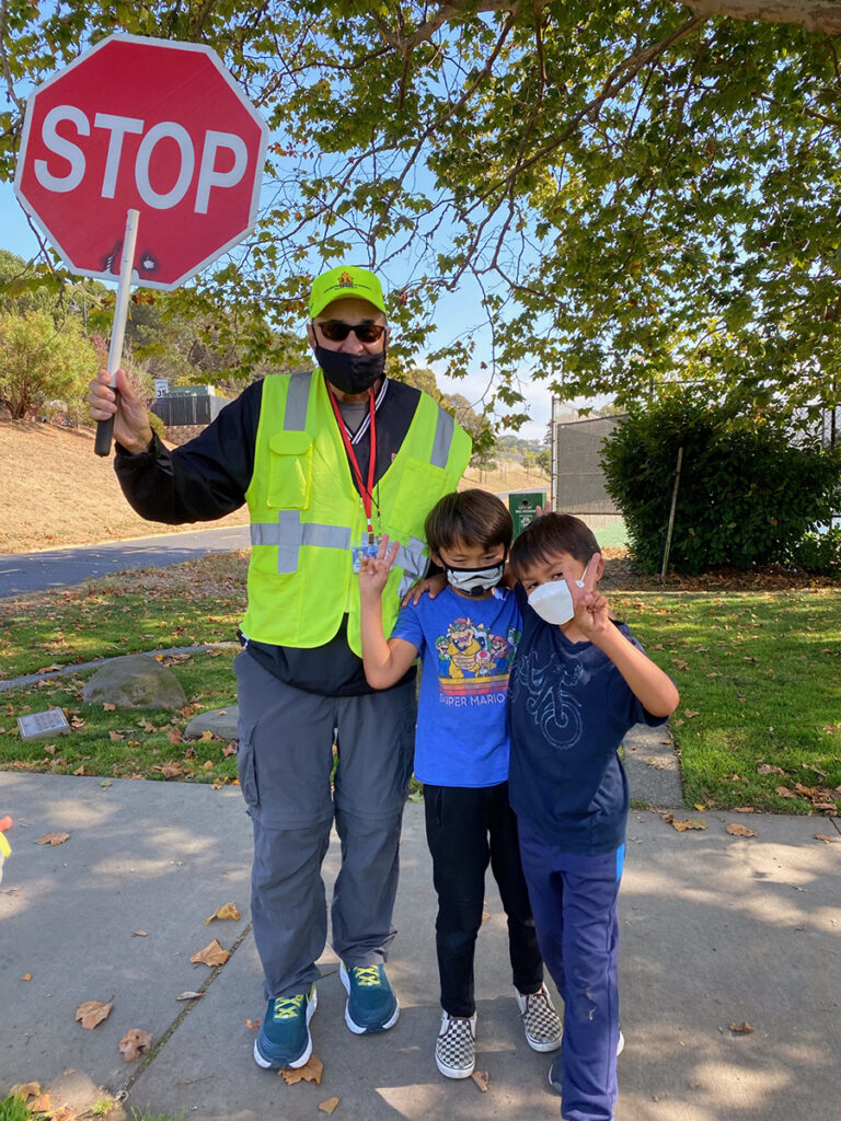 Two children take a picture with a crossing guard holding a stop sign