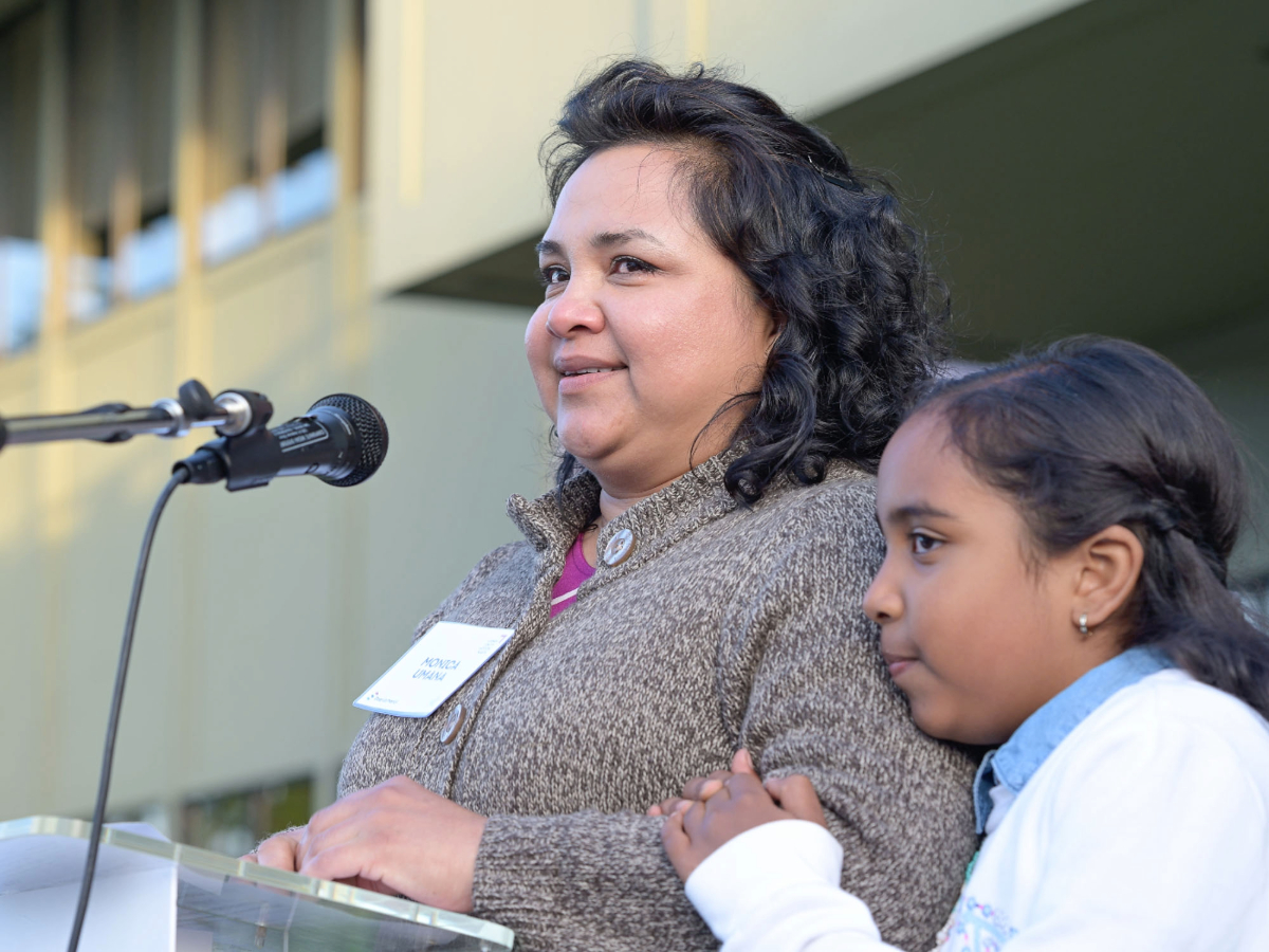 Monica Umaña stands at the podium holding her daughter’s hand as she accepts the 2025 Community Courage Award during Step Up Marin, both faces filled with emotion.