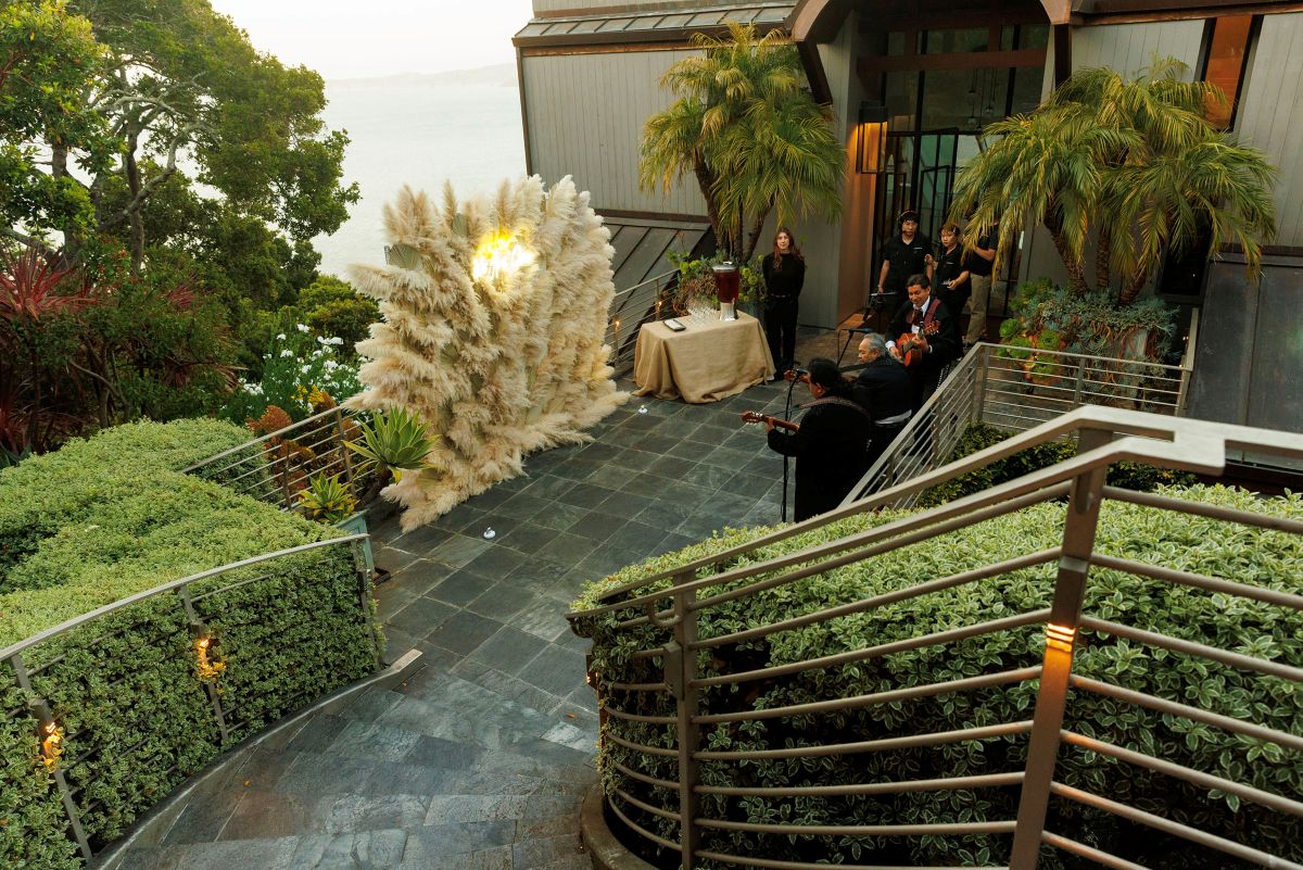 An outdoor entrance decorated with a large pampas grass installation, with live musicians performing beside it at the Tiburon residence.