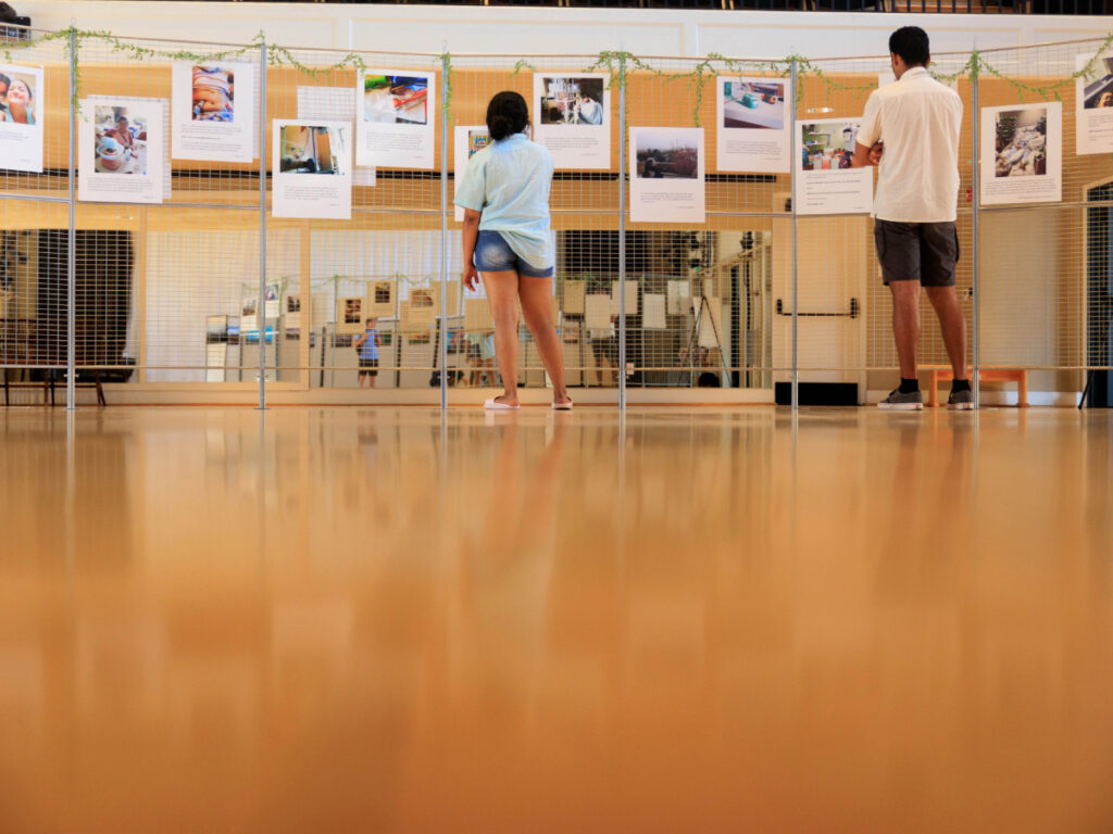 Visitors reading photo displays on panels at an exhibit.