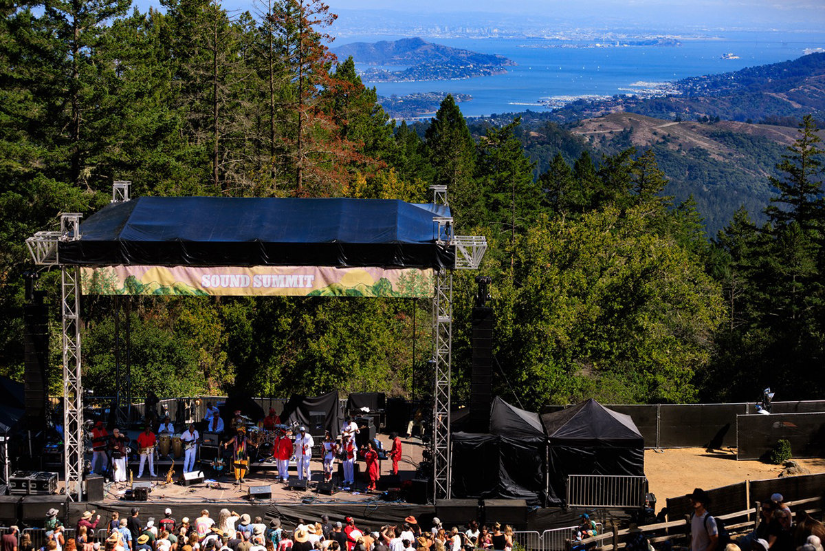 A large crowd of people enjoying a concert, focused on a vibrant stage with performers.