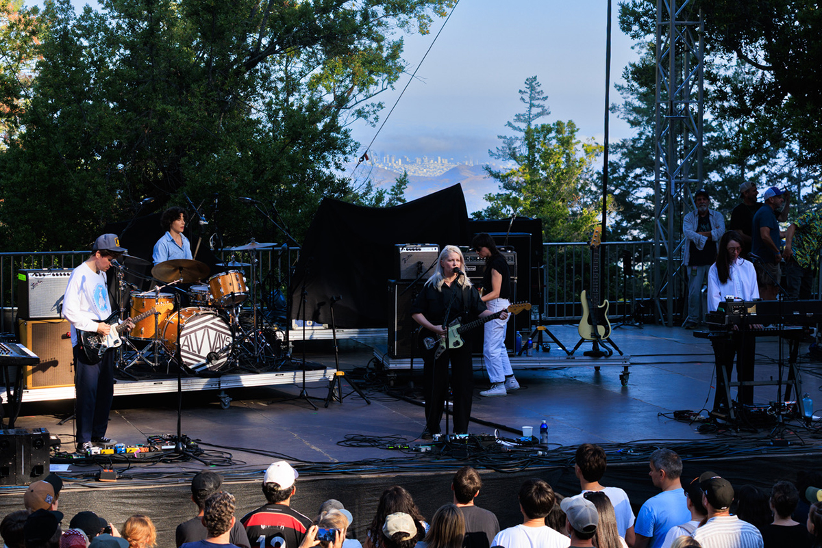 A group of people stands on stage with a band, engaging the audience during a live performance.
