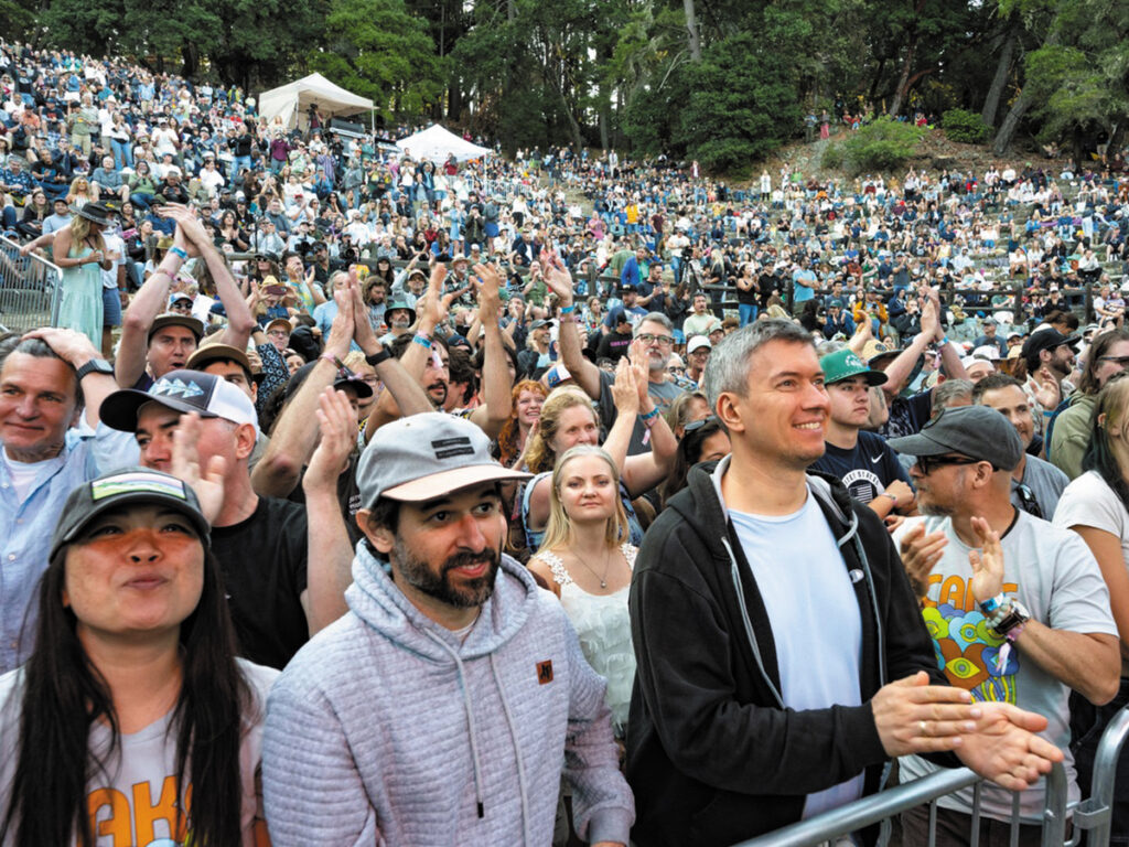 A lively concert crowd with one man prominently standing in the front, enjoying the performance.