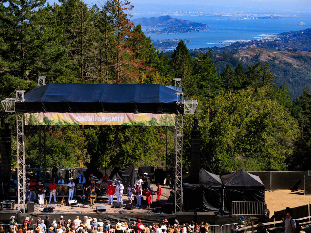 A large crowd of people enjoying a concert, focused on a vibrant stage with performers.