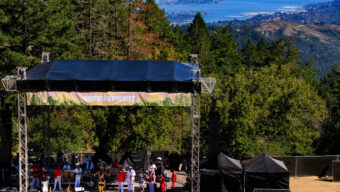 A large crowd of people enjoying a concert, focused on a vibrant stage with performers.