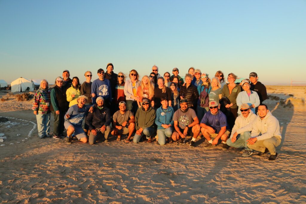 A group of people on a beach at sunset.