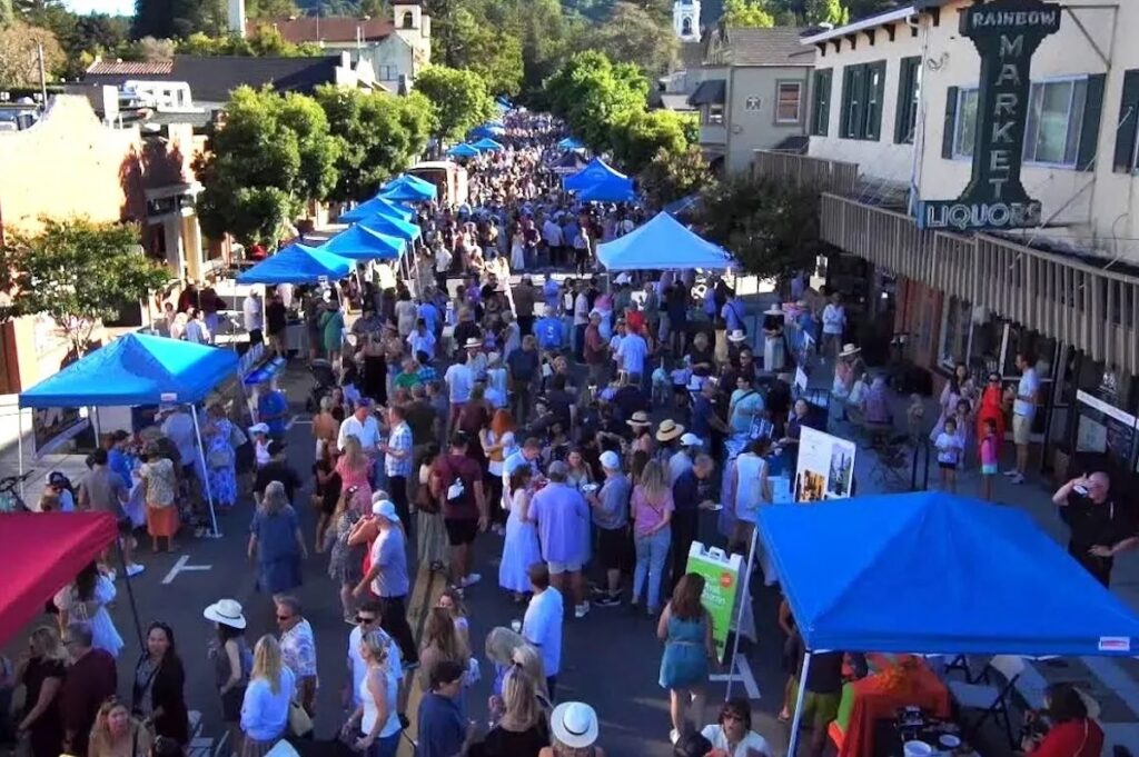 An aerial shot of people walking down a street with lots of pop-up tents.