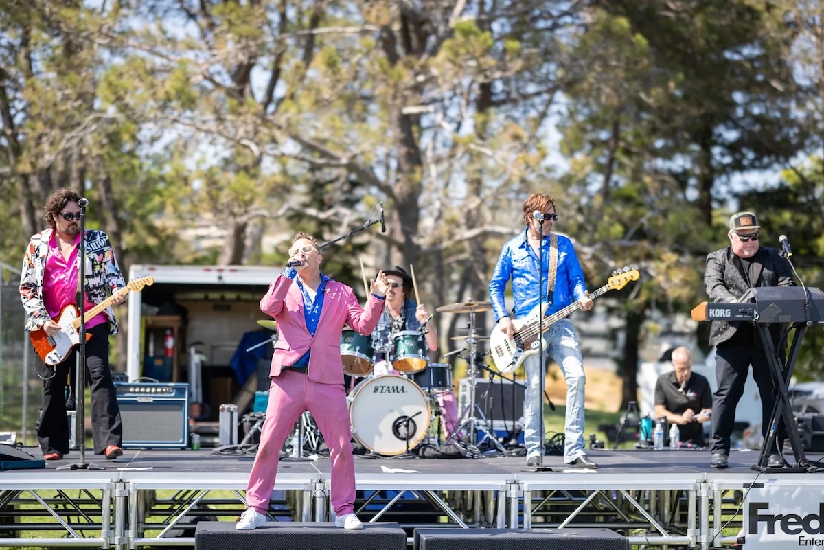 A band plays onstage outside/ in a park.