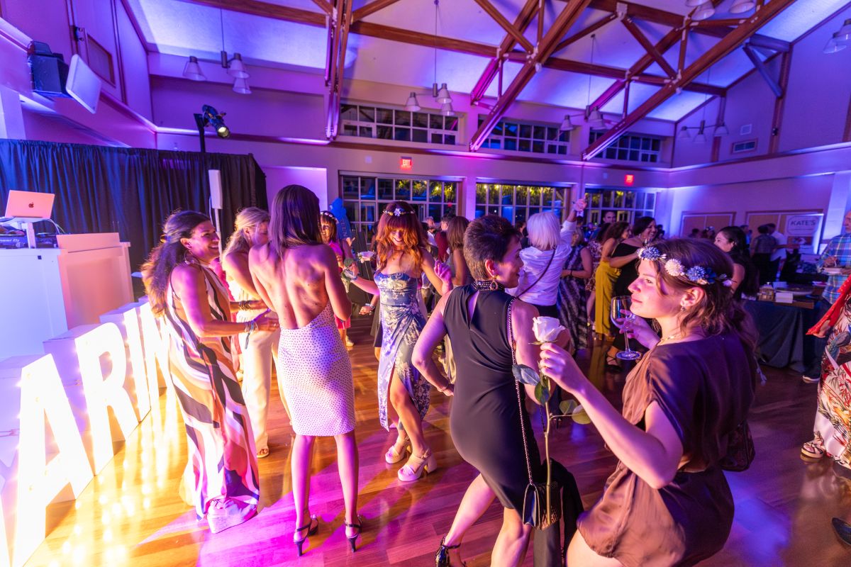 Guests dancing under purple and gold lights inside the Best of the County Bash.
