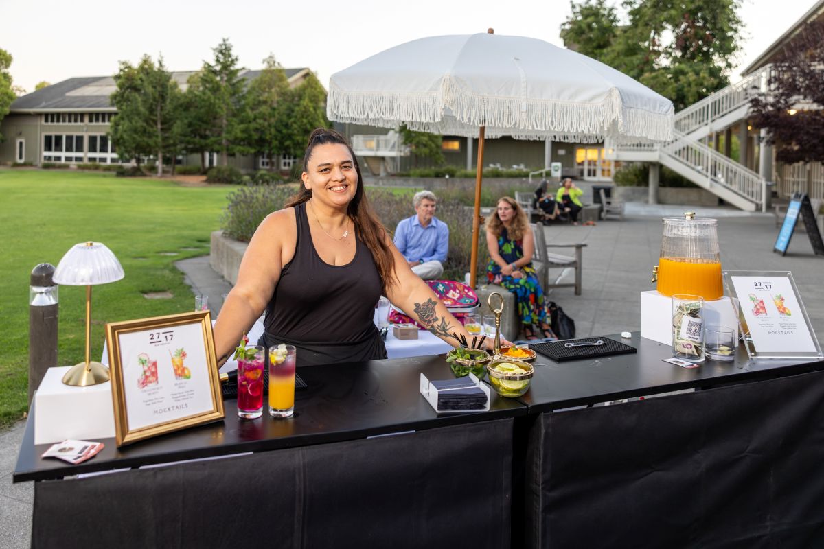 Bartender serving cocktails at outdoor mocktail bar.