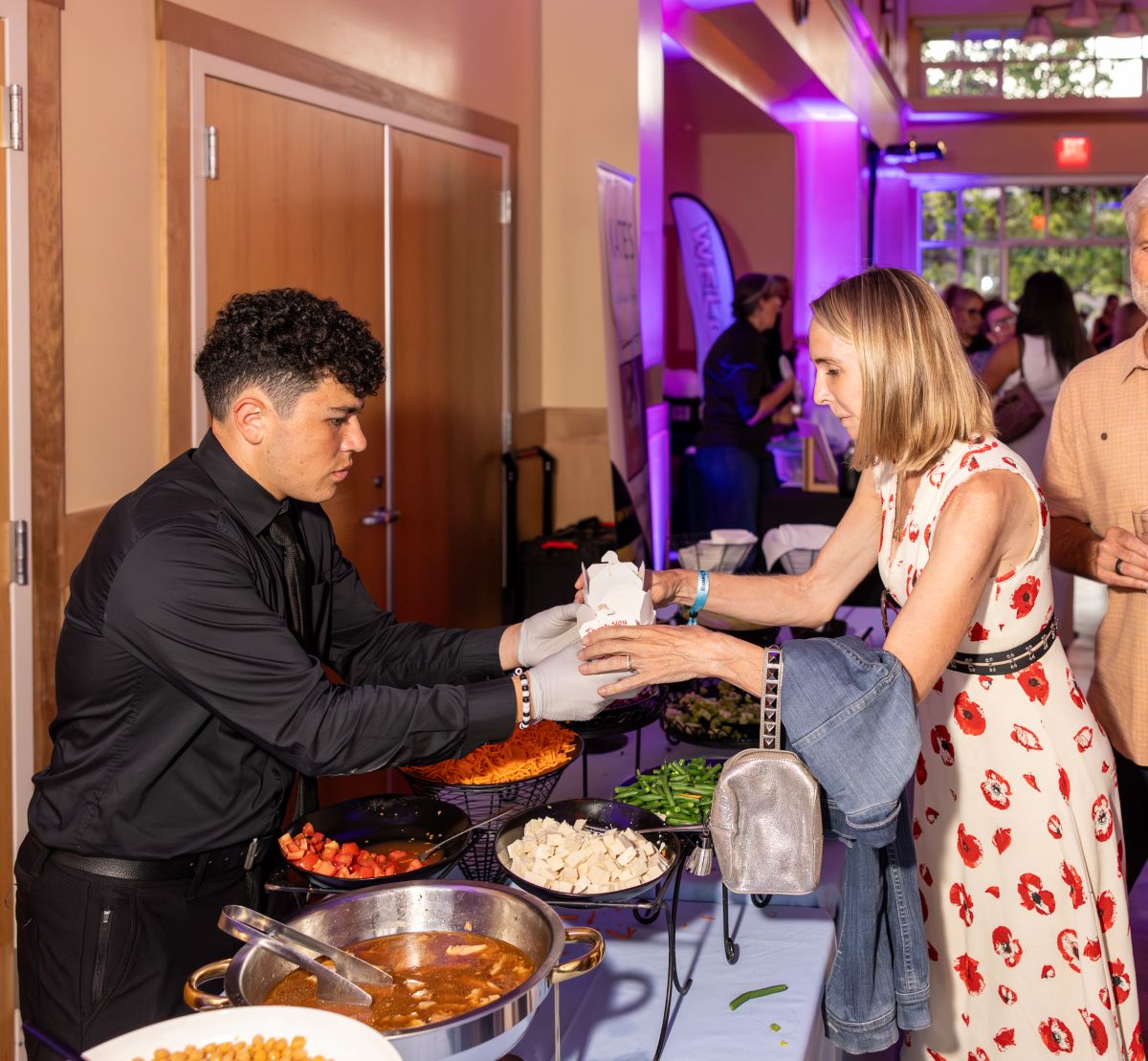 Server handing takeout container of food to guest.
