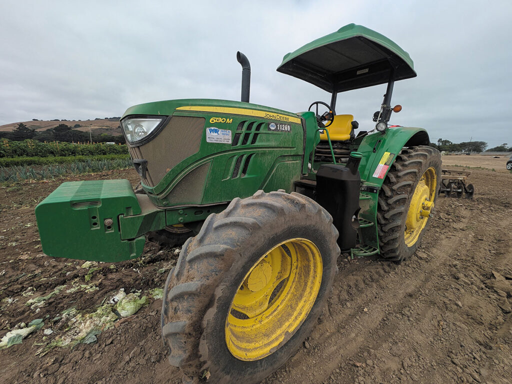 A tractor equipped with a large yellow wheel, highlighting its role in farming and land cultivation.