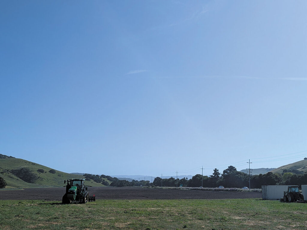 A tractor is stationary in a field, with a vibrant blue sky in the background.