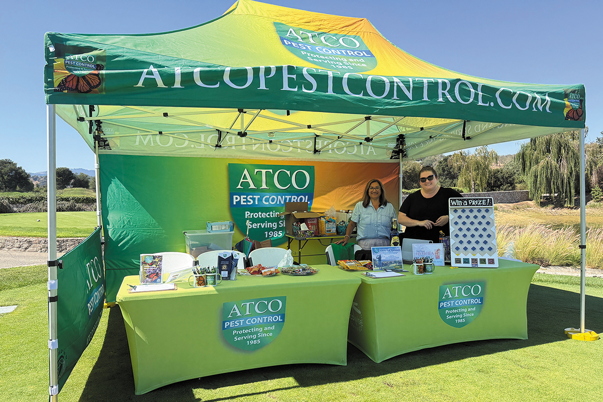 ATCO Pest Control booth displayed at the ATCO Golf Tournament, featuring promotional materials and staff engaging with attendees.