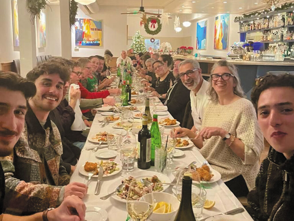 A group of people gathered around a long table filled with various dishes, enjoying a meal together.