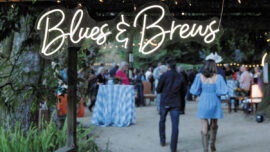 A colorful sign that says "Blues and Brews" at an outdoor festival, inviting guests to enjoy music and drinks.