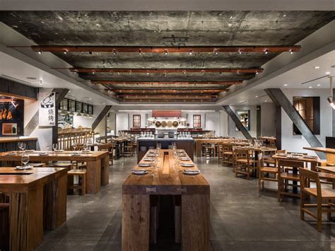 A spacious restaurant dining room with wooden tables and benches arranged for guests.