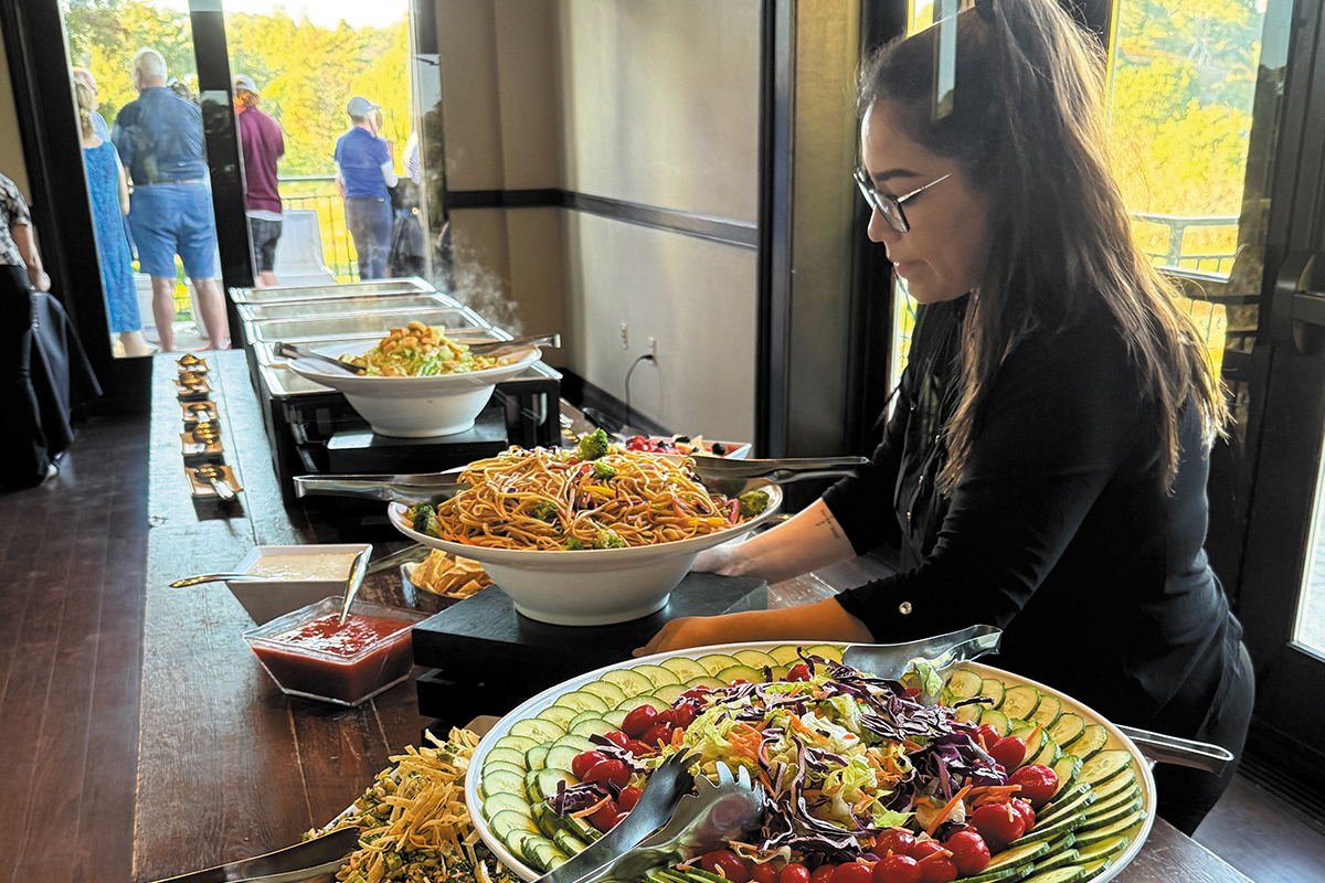 A woman is serving a meal to a group of people, creating a warm and inviting dining atmosphere.