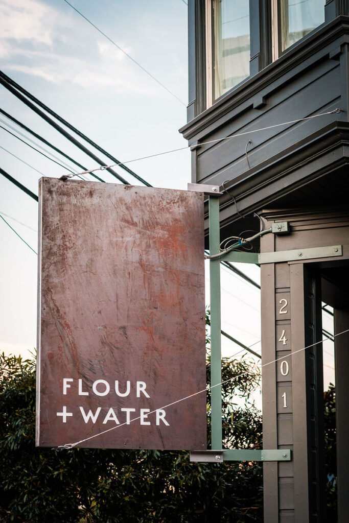 A restaurant sign that reads "flour + water," showcasing a contemporary style and inviting atmosphere.
