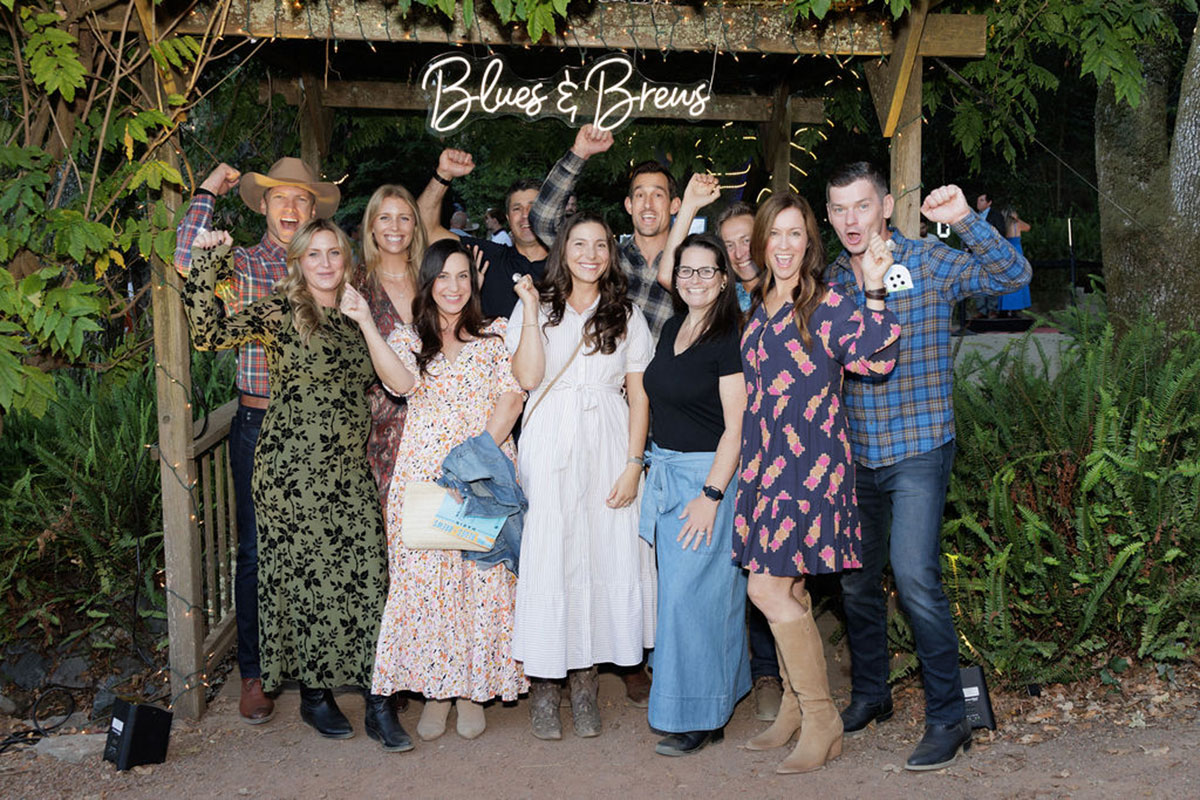 A cheerful group poses for a picture in front of a gazebo, showcasing a festive atmosphere in a garden.