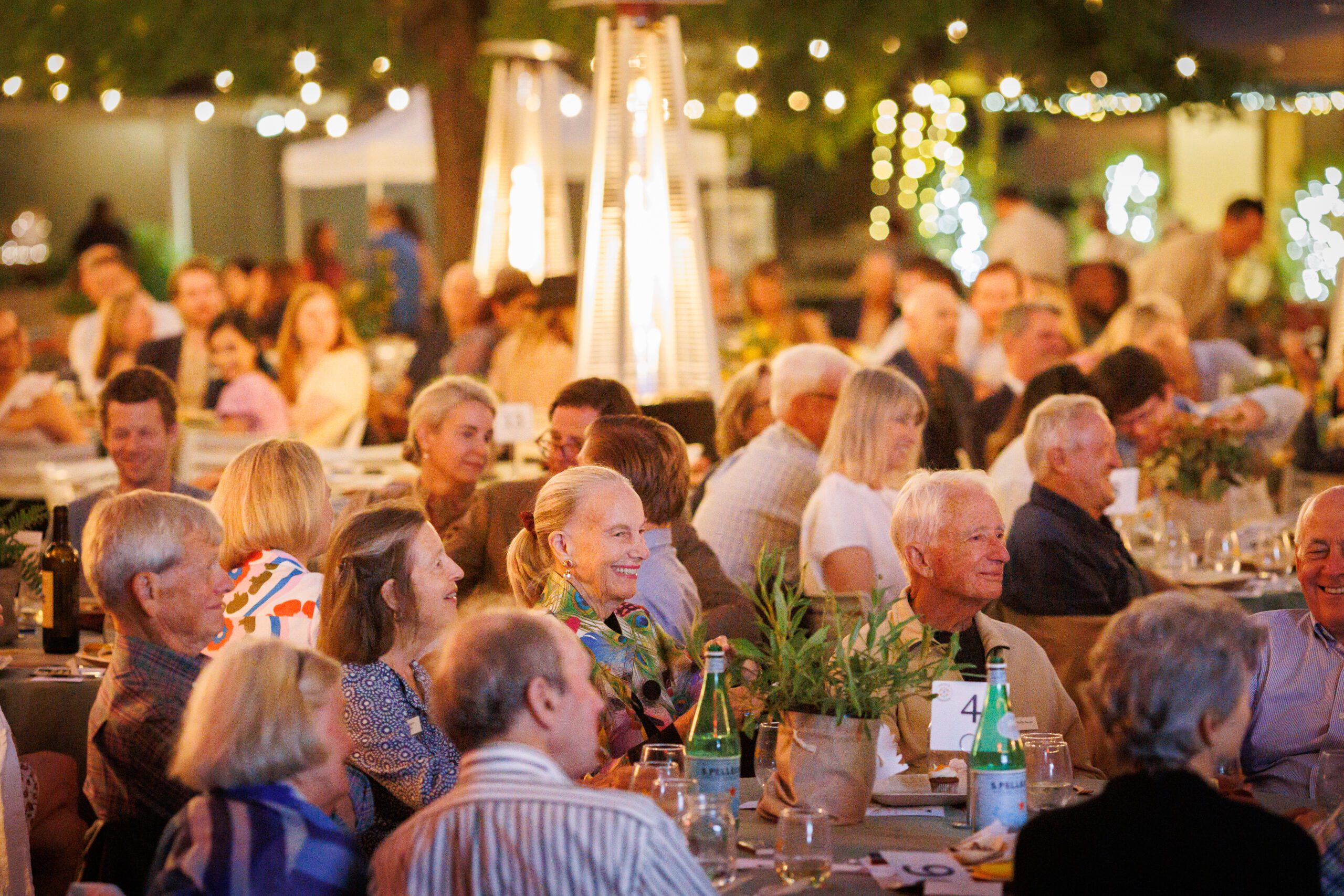 Guests sit at tables with many heat lamps around.
