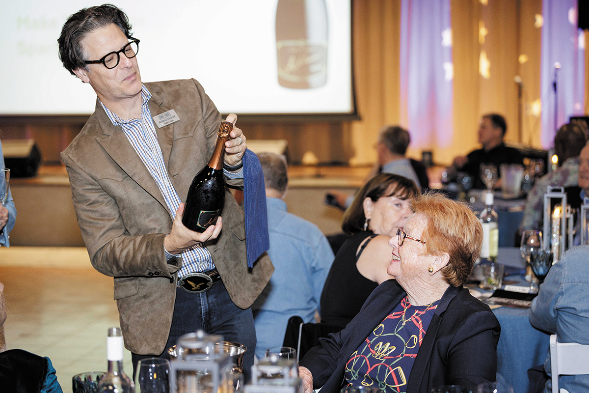 A man carefully opens a bottle of wine at a dinner setting, enhancing the meal's ambiance and enjoyment.