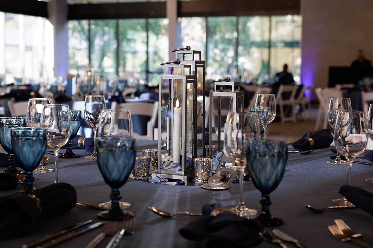A dining table covered with a blue cloth, elegantly set with silverware for a meal.