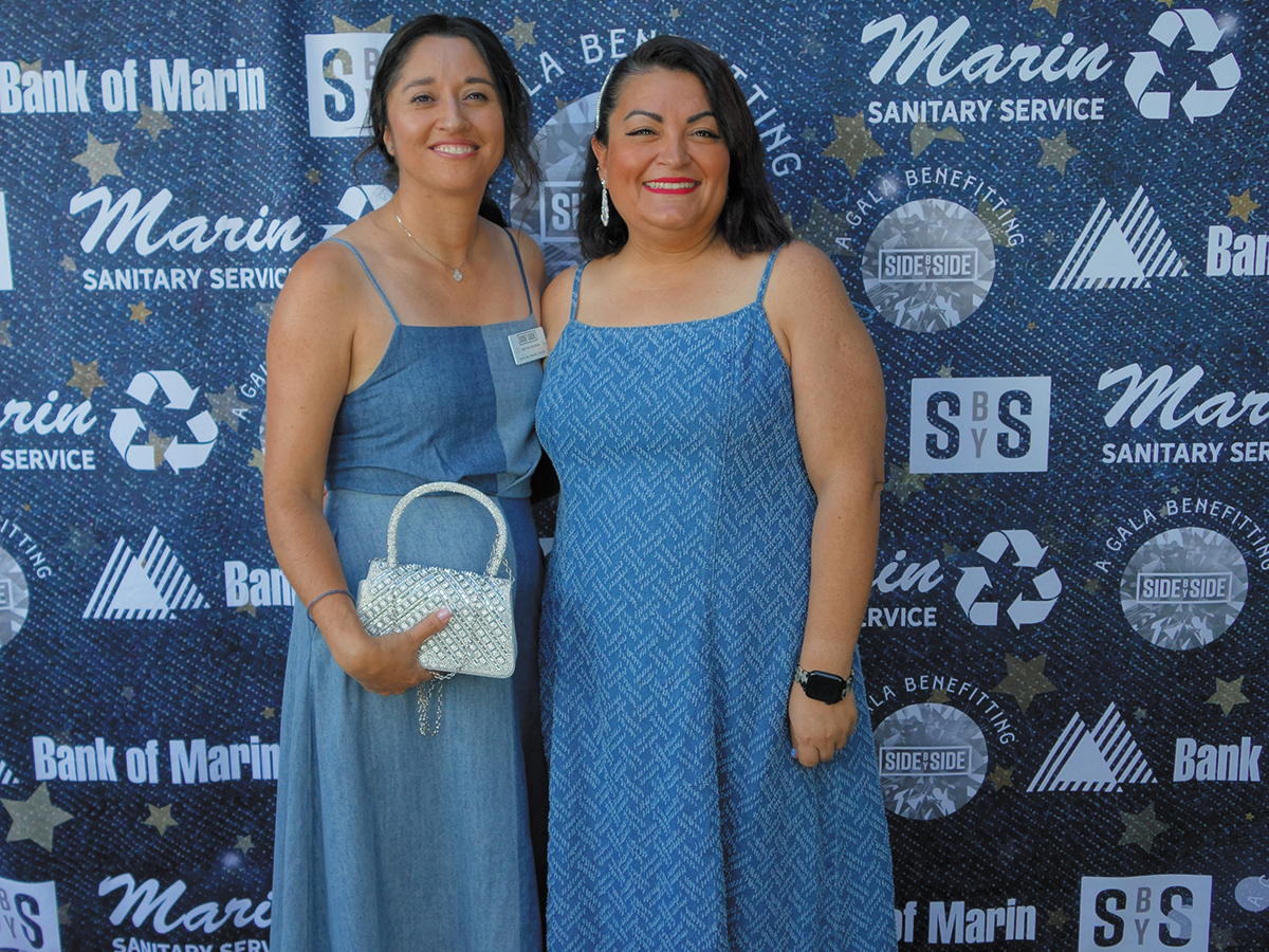 Two women in elegant blue dresses stand side by side for a photo.