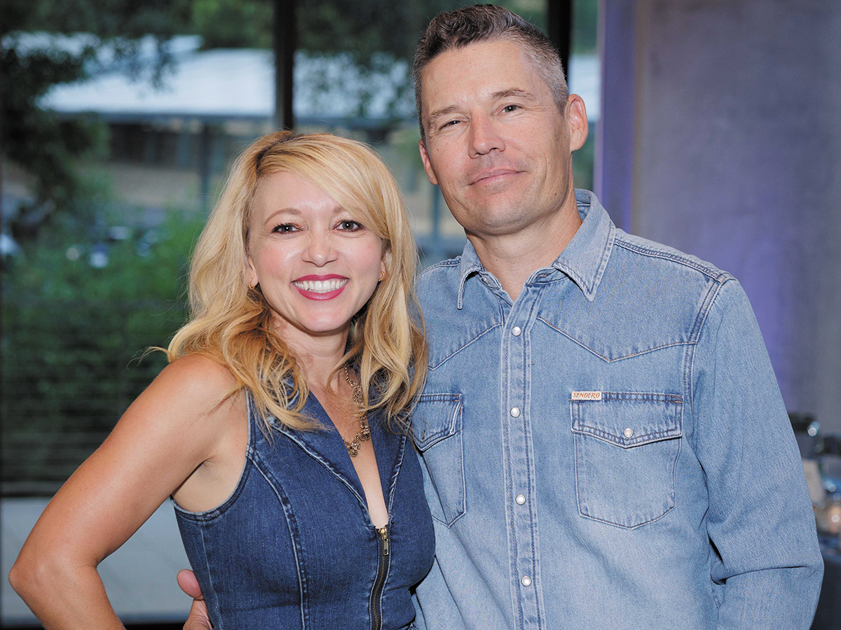 A man and woman smiling together for a photo at a social event, dressed in formal attire.