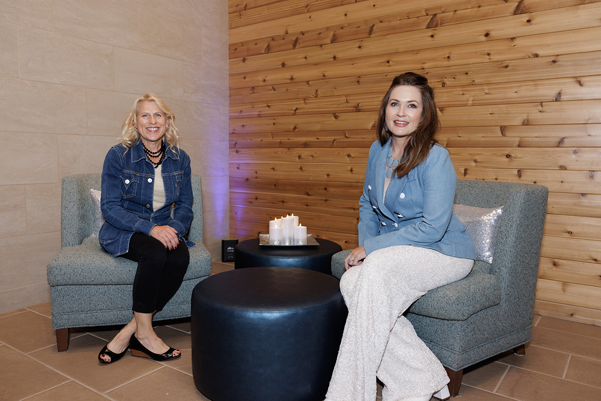 Two women sitting on chairs in a cozy room, appearing to discuss something thoughtfully.
