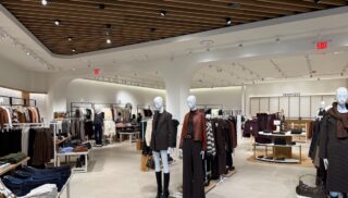 An overview of a store with racks of clothing and a few mannequins.
