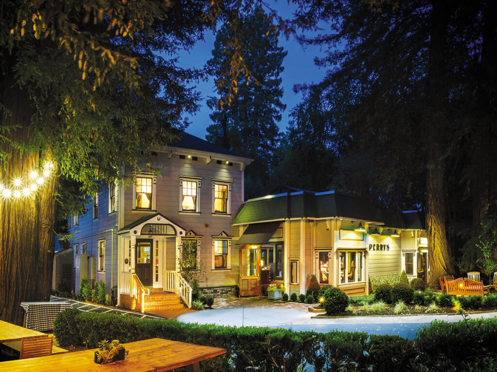 A large house with a patio and trees illuminated at night, creating a serene and inviting atmosphere.
