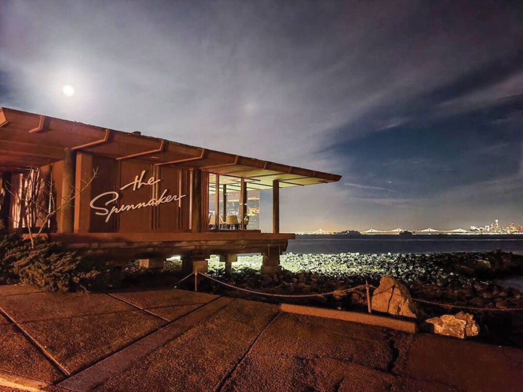 A bright moon shines over the dark ocean, creating a serene and reflective nighttime scene.